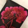Vegan leather clutch purse with hand-painted vibrant pink and red floral design, featuring detailed petal and leaf artwork, perfect for stylish accessories and unique fashion statements.