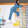 Colorful snacks in a convenience store with a woman climbing on stacked cereal boxes.