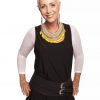 Vibrant woman wearing bold yellow and silver statement jewelry, stylish black and white outfit, standing confidently with hands on hips.