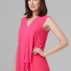 Elegant pink sleeveless blouse with a front drape, perfect for summer or business casual outfits, styled with white pants.