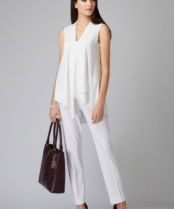 Elegant woman in white sleeveless blouse and trousers holding a designer handbag, showcasing stylish professional fashion for modern women.