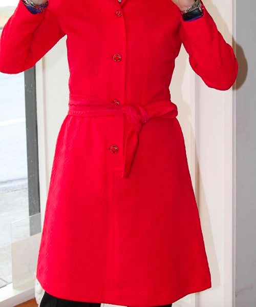 Bright red personalized tailored coat with a waist tie, stylish button details, and textured fabric perfect for fall and winter fashion. Handcrafted by Katy Amaker for unique, chic outerwear.