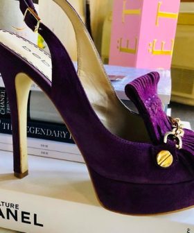 Luxurious purple velvet high-heeled shoe with bow detail and gold accents, perfect for elegant fashion statements and special occasions.