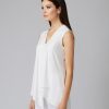 Elegant white sleeveless blouse with V-neck and draped front, perfect for sophisticated and modern fashion looks, as showcased by a stylish model.