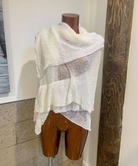 Soft beige knit shawl draped over mannequin torso, perfect for layering and cozy winter styling.