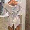 Soft beige knitted women's top with ruffle and tie closure, versatile fashion piece perfect for casual or elegant outfits, displayed on a mannequin in a boutique setting.