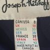 Bright clothing tag showing size and country information, including Spain, France, Mexico, UK, Italy, and Canada, on a black fabric background.