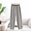 Black and white striped wide-leg pants with elastic waistband, perfect for casual or stylish outfits, displayed on a hanger in a minimal bedroom setting.