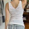 Soft white sleeveless tank top on woman, casual fashion outfit, cozy comfort wear for summer or relaxed days, styled with light blue denim jeans, interior background.