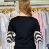 Black and white striped long sleeve sweater on woman in clothing store.