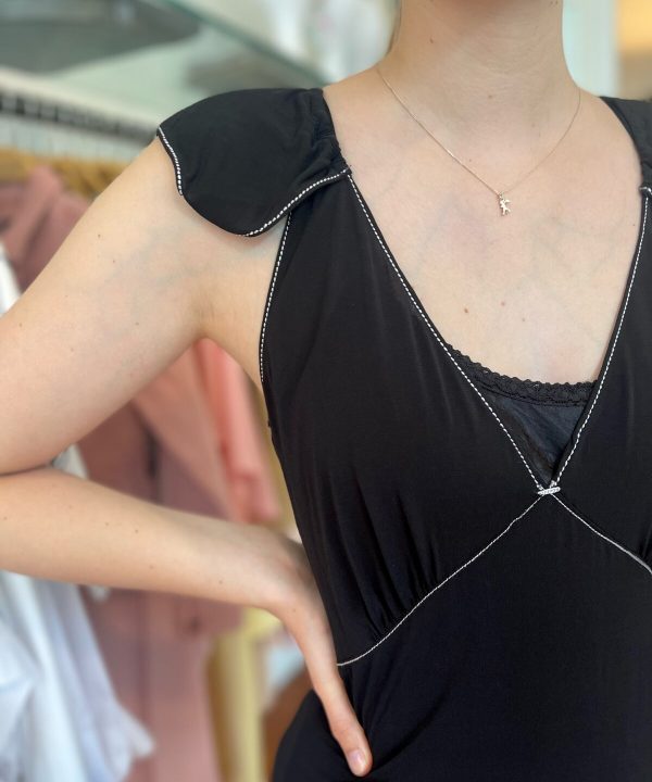 Delicate silver unicorn necklace on a woman's neck, black sleeveless dress with ruffled shoulder and stitched detail, stylish jewelry for women, trendy accessories for modern fashion.