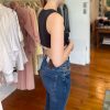 Black sleeveless crop top paired with high-waisted blue jeans in a boutique clothing store.