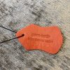 Smooth genuine orange leather tag with embossed text 
