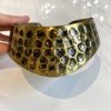 Intricate gold honeycomb patterned cuff bracelet with textured hexagonal details, stylish jewelry accessory, handmade luxury jewelry, and modern artisan design.