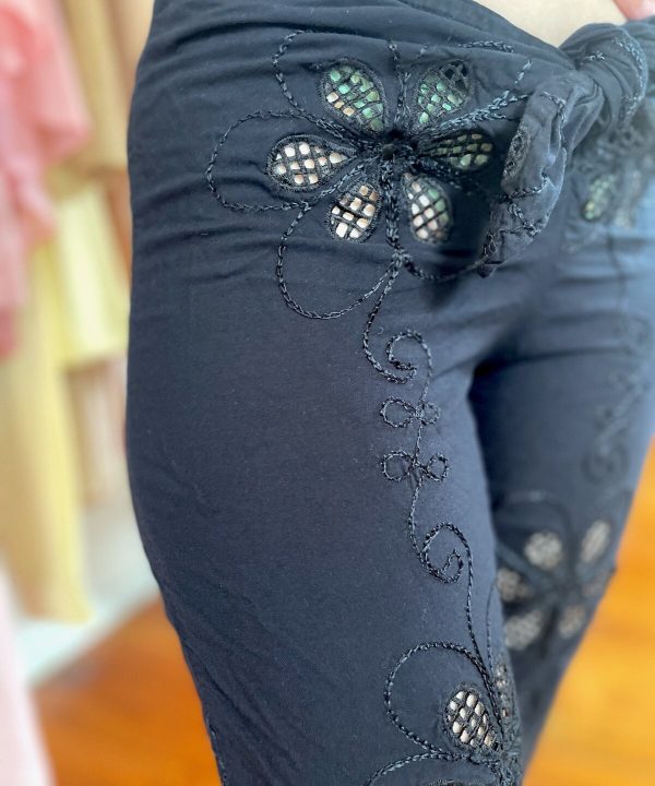 Floral embroidery on navy blue pants showcasing intricate crafted details and stylish fashion design.