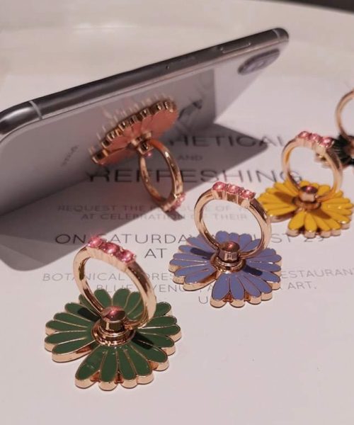 Colorful enamel floral hoop earrings displayed on a white surface with a smartphone nearby, showcasing trendy jewelry designs.