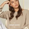 Soft beige knit sweater fashion portrait of a young woman with long wavy brown hair, natural makeup, and thoughtful expression, representing stylish casual wear from Italy, brand Gran Sasso.