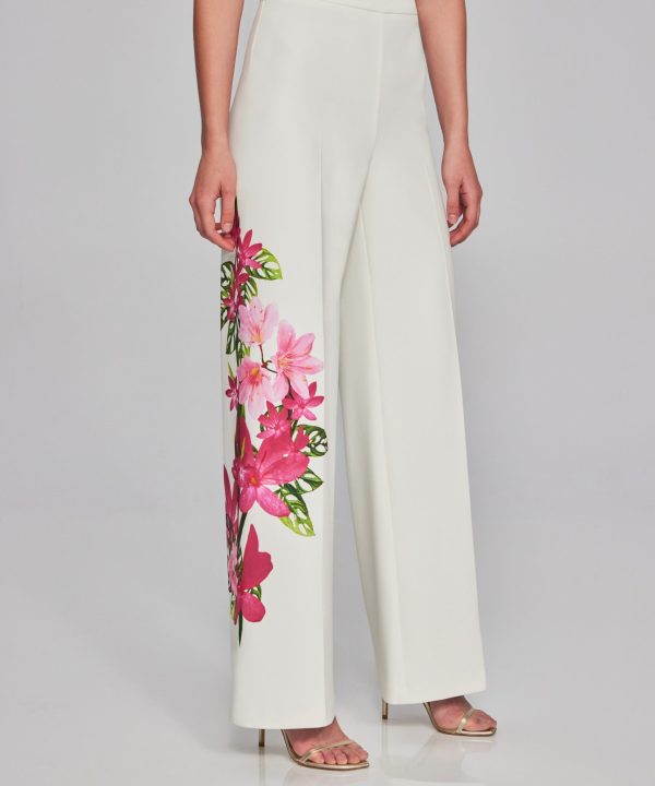 Elegant white wide-leg pants featuring vibrant pink floral embroidery, perfect for boutique fashion and designer clothing enthusiasts, styled with heels for a chic and modern look.
