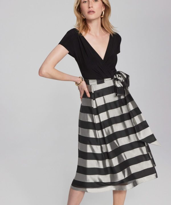 Black V-neck top paired with a high-waisted black and white striped midi skirt featuring a bow tie detail, stylish and contemporary fashion ensemble.