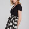 Elegant black wrap top paired with a stylish black and white striped satin skirt with a bow, perfect for chic casual or dressy occasions.