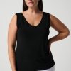 Elegant black sleeveless V-neck top for women, perfect for casual or office wear, styled with white pants, showcasing timeless fashion and versatile wardrobe essentials.