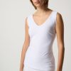 Soft white sleeveless V-neck top worn by a young woman with short red hair, showcasing minimalist fashion and comfortable summer style.