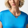 Elegant blonde woman in blue satin top with modern jewelry, showcasing fashion and style photography for Katya Maker, fashion designer and influencer, promoting contemporary chic attire.