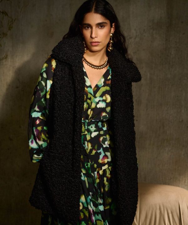 Vibrant abstract print silk dress paired with a cozy black textured coat, accessorized with bold gold jewelry, showcasing modern bohemian fashion by Katyamaker.