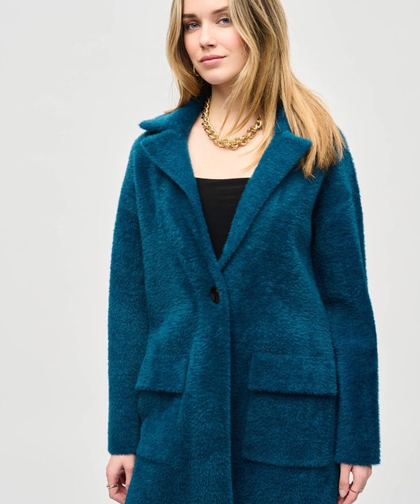 Soft teal fuzzy coat with oversized collar and large front pockets, styled with a black top and gold chain necklace, showcasing cozy winter fashion for women.