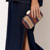 Striped fabric clutch bag with marble ring accessory held by a woman in denim outfit.