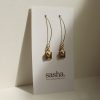 Delicate gold dangle earrings with heart and square charms displayed on a white sash jewelry card, highlighting handmade jewelry design by Sasha Jewelry.
