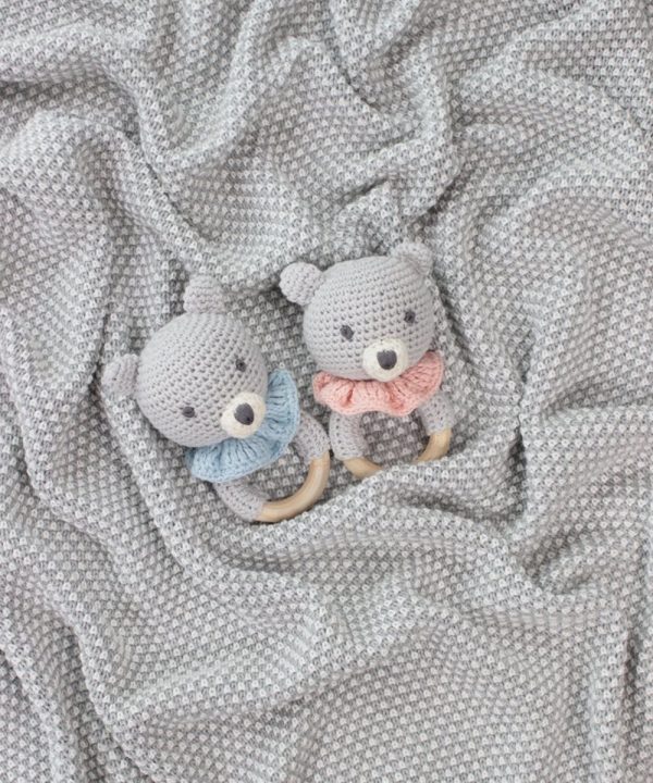 Soft crochet teddy bear baby rattles on textured grey blanket, adorable handmade nursery decor, perfect for baby shower gifts, safe and cozy for infants, crafted with care for newborns and young children.