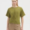 Soft green short-sleeve knit top styled with beige trousers, minimalist fashion, casual chic, spring/summer look, simple elegance, comfortable women's clothing, modern wardrobe essential.