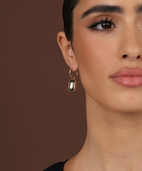 Elegant statement earring featuring a geometric gemstone pendant, worn by a woman with flawless makeup and dark hair, showcasing jewelry styling for fashion and accessories.