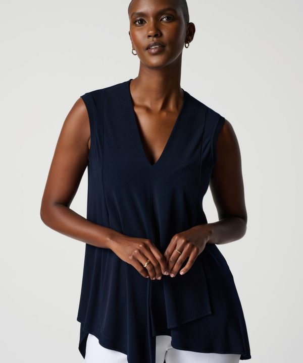 Navy sleeveless blouse with V-neck, stylish women's fashion, elegant top for professional or casual wear, paired with white pants, minimalist studio photography.