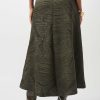 A-line wide-leg skirt with a textured tropical leaf pattern in olive green, paired with high-heeled boots, styled for fashion-forward women.