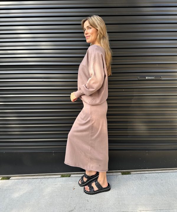 Comfy casual outfit featuring cozy blush sweatshirt and matching maxi skirt with black platform sandals against a modern black metal wall.