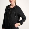Elevated black hooded utility jacket with gold accents, stylish and versatile, perfect for fashion-forward women seeking comfort and chic streetwear.