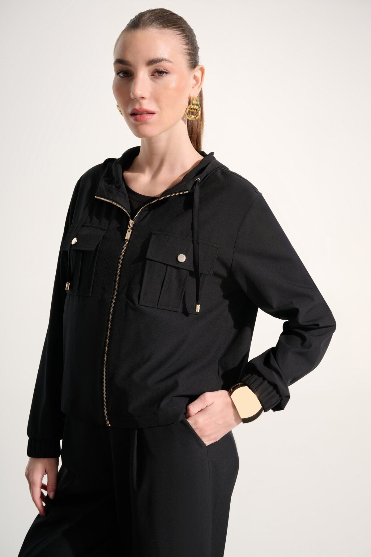 Elevated black hooded utility jacket with gold accents, stylish and versatile, perfect for fashion-forward women seeking comfort and chic streetwear.
