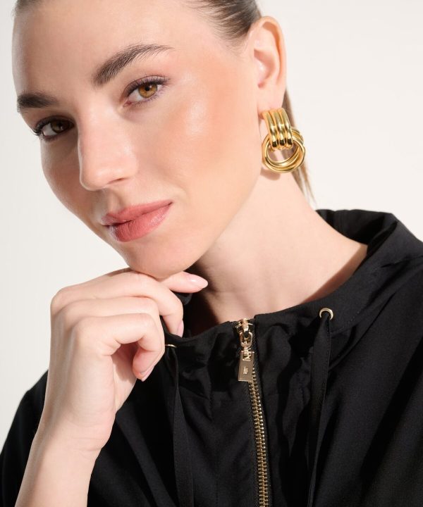 Elegant woman wearing statement gold earrings and a black hoodie, showcasing contemporary jewelry design and fashion accessories. Perfect for stylish, modern jewelry enthusiasts.