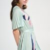 Elegant woman modeling a stylish floral pleated dress with ruffled sleeves, perfect for spring and summer fashion.