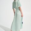 Soft mint green pleated midi dress with short sleeves and a waist tie, styled with nude heels, perfect for stylish summer or cocktail events.
