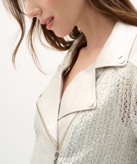 Elegant fashion model wearing a shimmering metallic jacket with textured details, showcasing stylish jewelry and refined accessories for modern, sophisticated looks.
