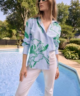 1. Stylish woman wearing a blue and green floral print shirt, white pants, and eco-friendly sunglasses by the poolside on a sunny day, showcasing fashion from katyamaker.