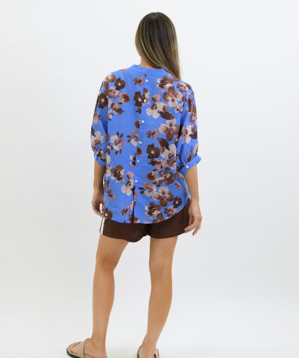 Bright blue floral blouse with button details, styled casually for everyday wear.