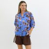 Elegant blue floral blouse with a relaxed fit, paired with brown shorts for a stylish summer look, perfect for casual outings and outdoor events.