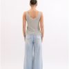 Soft grey sleeveless tank top with a V-neck, paired with light-wash wide-leg jeans, showcasing casual summer fashion. Perfect for a relaxed, stylish look.
